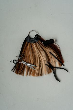 Farbmuster aus Haarsträhnen in Blond-, Braun- und Kupfertönen, daneben eine Schere